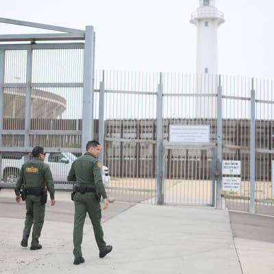 Vartijat kävelevät kohti Yhdysvaltojen ja Meksikon välistä rajavyöhykettä eristävää aitaa.