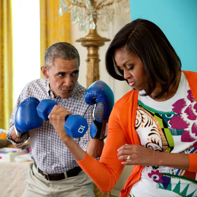 Presidentti Barack Obama hassuttelee nyrkkelyhanskat kädessä vaimonsa Michellen kanssa, joka pitää toisessa kädessään käsipainoa.