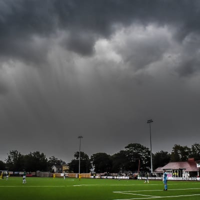 Mörka moln ovanför fotbollsplanen.