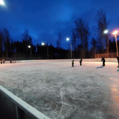 Barn skrinnar och spelar med klubbor på Isnäs sportplan.