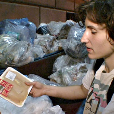 Nuori mies etsii kaupan pois heittämää ruokaa jäteastiasta