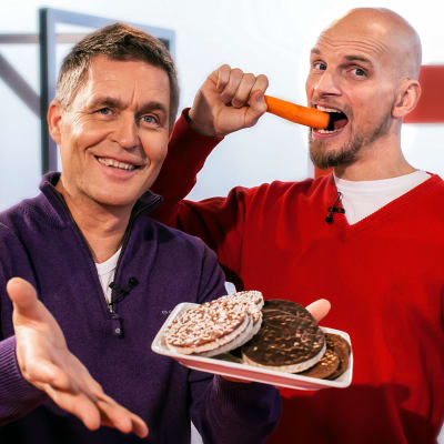 Risto Laitila pitää kädessään keksilautasta. Mikko Penttilä syö taustalla porkkanaa.