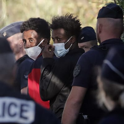 En grupp migranter som har anlänt till Frankrike och eskorteras av polis