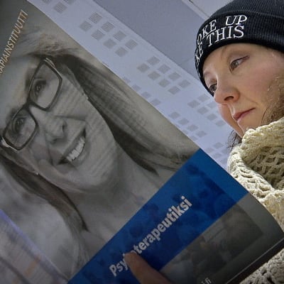 Nainen lukee Helsingin psykoterapiainstituutin esitettä.