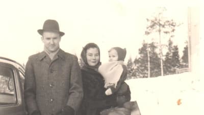 Laura Kolbe med föräldrar 1959 på vinter vid bil. Laura i mammas famn.
