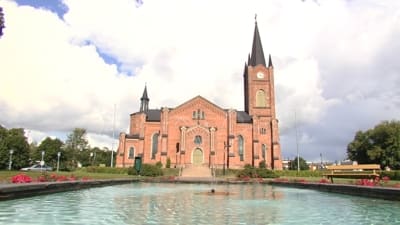 Lovisa kyrka i solsken, vattenfontän i förgrunden