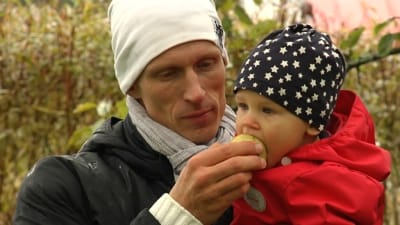 Olli Ilander äter äppel tilsammans med sin son