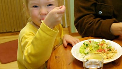 Litet barn stoppar mat i munnen.
