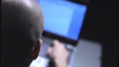 En person som sitter vid en laptop, bakgrunden är suddig.