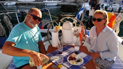 en vkinna och en man dricker vin i sittbrunnen i en segelbåt