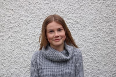 Emma Heiniö framför en stenvägg.