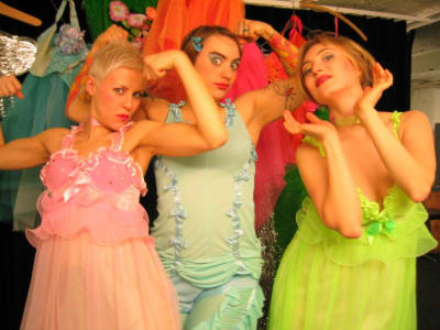 Annamari Vänskä, Roosa Voima ja Veera Voima poseeraavat kameralle kädet koholla prinsessamaisissa asuissa.