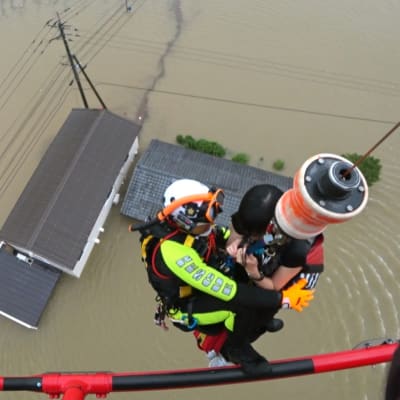 En räddningsarbetare hissar upp en invånare i en helikopter från ett översvämmat hus i prefekturen Saga i sydvästra Japan.