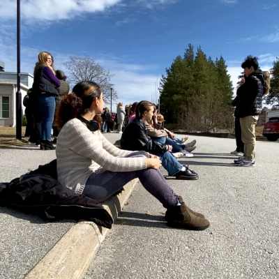 Studerande sitter på en trottoarkant.