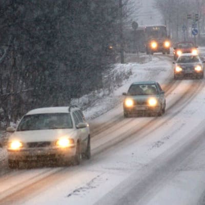Bilar och en buss kör på hal och snöig väg.