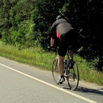 En landsvägscyklist blir omkörd av en personbil.