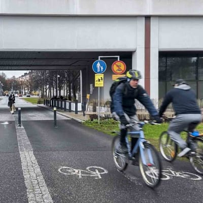Personer cyklar och går genom en tunnel. En skylt verkar visa att cykelvägen blir till gångbana i tunneln.