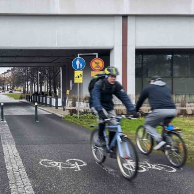 Personer cyklar och går genom en tunnel. En skylt verkar visa att cykelvägen blir till gångbana i tunneln.