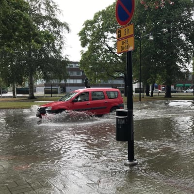 En bil kör genom cirka 30 centimeter djupt vatten i centrum av Raumo.