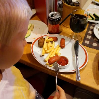 Poika syö lastenateriaa ravintolapöydässä