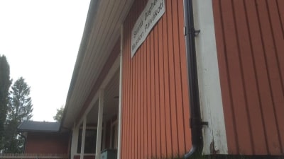 Ett rött daghemshus i trä, en sliten husknut.