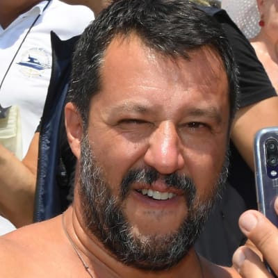 Inrikesminister Matteo Salvini tar en selfie med en anhängare på en strand i Taormina, Sicilien. Båda har bar överkropp.