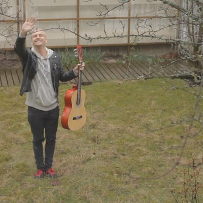 Janne Grönroos vinkar med en gitarr i handen