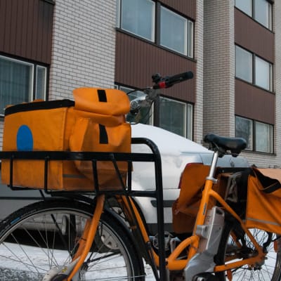 Postinjakajan polkupyörä pysäköitynä kerrostalon eteen talvella.