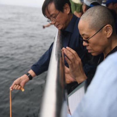 Liu Xiaobos änka Liu Xia (till höger) tillsammans med Liu Xiaobos yngre bror sprider den avlidne fredspristagarens aska i havet.  