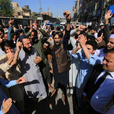 Pakistanilaisia mielenosoittajia kädet ilmassa kadulla, taustalla rakennuksia.