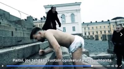 Halvnaken man kryper upp för Domkyrkans trappor i Helsingfors i video mot den obligatoriska svenskan som gjorts av Sannfinländska ungdomsförbundet.
