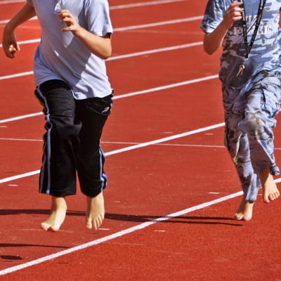 Kaksi poikaa juoksee liikuntatunnilla.