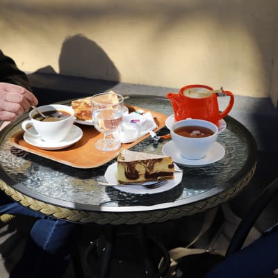 Två personer sitter vid ett kafébord med var sin kaffe och tårtbit.