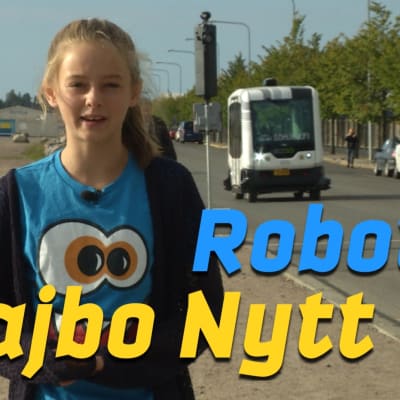 Maddie står vid vägkanten med en robotbuss i bakgrunden