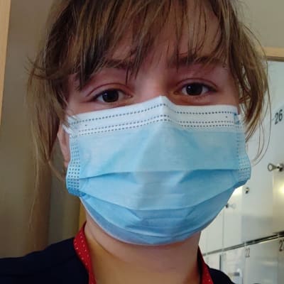Sjukskötare med ansiktsmask och arbetskläder 