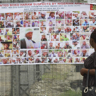 En kvinna tittar på en affisch med bilder av efterlysta misstänkte Boko Haram-anhängare.