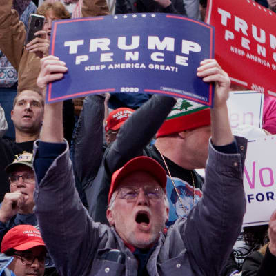 En bild på massa människor som ropar och håller i plakat där det står "Trump Pence". Plakaten är röda, blåa och vita.
