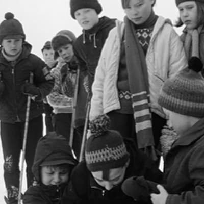 Koulupojat auttavat loukkaantunutta ystäväänsä hiihtomäessä (1966).