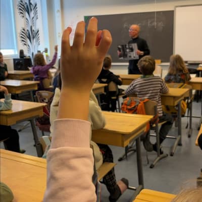 En uppstäckt hand i ett klassrum. 