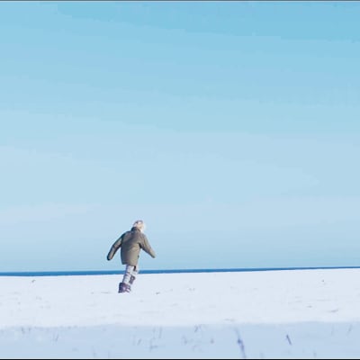 En barn springer på ett öppet fält täckt av snö.