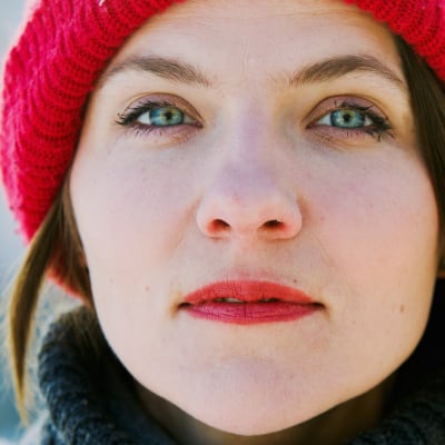 Anna Paavilainen katsoo intensiivisesti kameraan punainen pipo päässään.