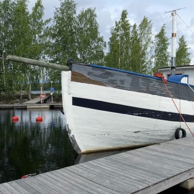 Vanha ja iso, sinivalkoinen troolari ankkuroituna vierasvenelaituriin.