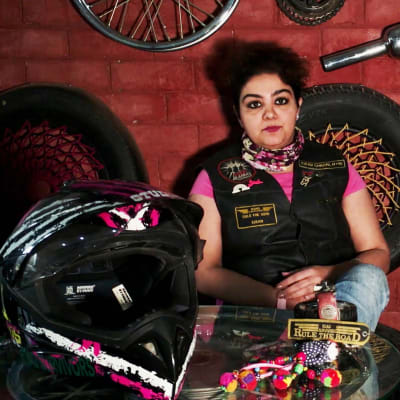Intialainen nainen moottoripyöräaiheisten tavaroiden ympäröimänä.