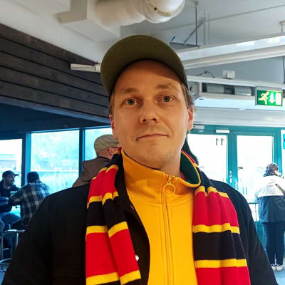 Man med skärmmössa och halsduk.