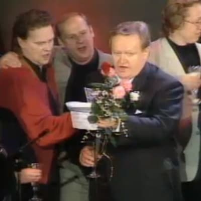 Presidentiksi valittu Martti Ahtisaari laulaa Helsingin työväentalolla, lavalla mm. Pepe Willberg, Jyrki Kovaleff, Eeva ja Marko Ahtisaari.