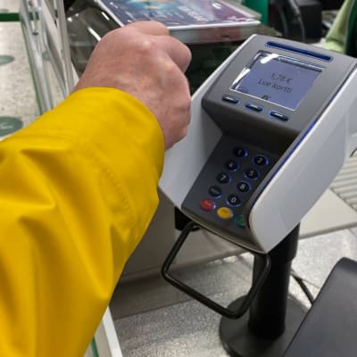 En kund som betalar sina uppköp vid en butikskassa. 