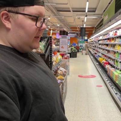 Nuori mies seisoo kaupassa kylmähyllyn edessä