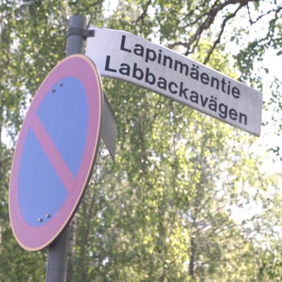 En trafikskylt med vägnamnet "Labbackavägen". I bakgrunden syns träd.