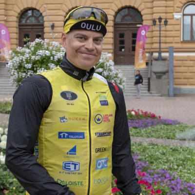 Romppainen seisoo Oulun kaupungintalon edustalla hymyillen kameralle