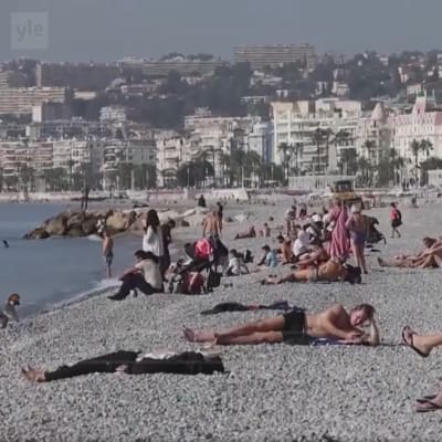 Folk ligger och solar sig på en strand vid Franska rivieran.